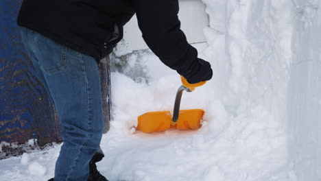 Close-up-of-man-shoveling-snow-in-front-of-a-barn