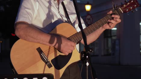 Musician-in-a-white-shirt-plays-an-acoustic-guitar-at-night