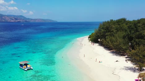 Ruhiger-Weißer-Strand-Einer-Tropischen-Insel-Mit-üppiger-Vegetation,-Vor-Anker-Liegende-Boote-Warten-Auf-Touristen,-Die-Die-Besten-Reiseziele-Auf-Bali-Besuchen