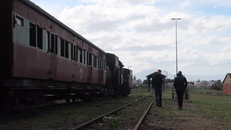 Two-teenage-boys-walking-along-side-train-carriage-and-disused-railway-line