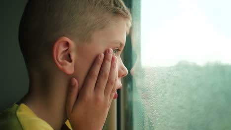 Looking-kid-at-rain-through-a-window