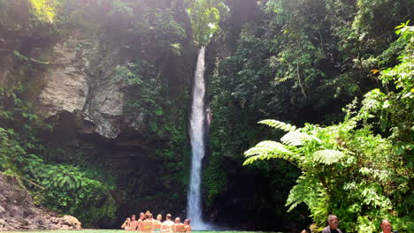 Group-of-tourists-or-people-gathering-and-swimming-just-below-the-cascade-of-water-falling-from-height