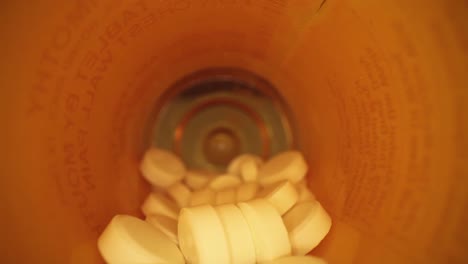 pulling-out-of-the-entire-length-of-an-orange-prescription-pill-bottle,-revealing-empty-blue-bottle-cap