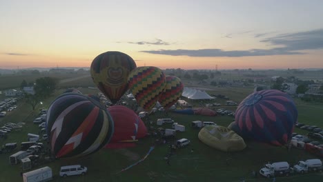 Aerial-View-of-a-Sunrise-Hot-Air-Balloons-Taking-Off-at-a-Balloon-Festival-on-a-Clear-Summer-Morning
