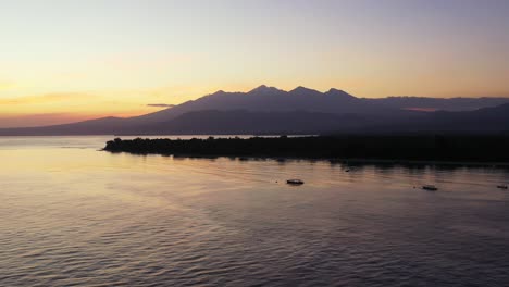 Gelber-Sonnenuntergang-über-Einem-Großen-Gewässer-Mit-Einer-Kleinen-Insel-Und-Bergen