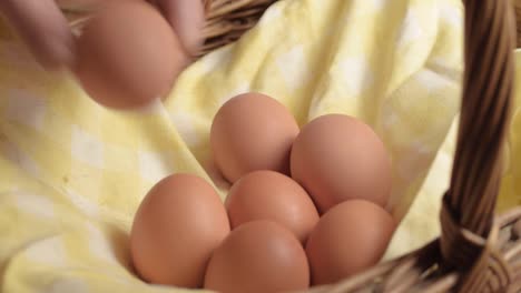 Hand-getting-fresh-brown-eggs-out-of-a-woven-basket