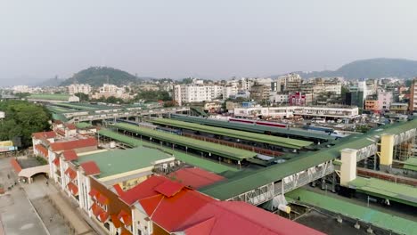Aerial-view-of-train-station-in-the-middle-of-Indian-city-of-Guwahati,-long-trains-waiting-on-platforms-for-passengers-to-get-on-board
