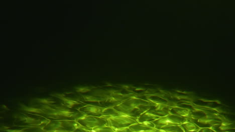Underwater-green-and-dark-sea-floor-with-caustics-at-bottom-of-ocean