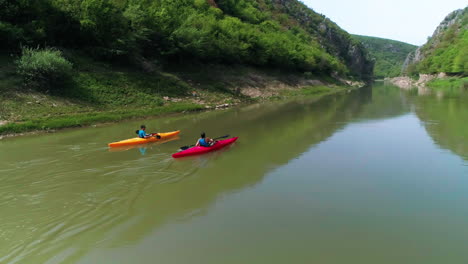 Sweeping-aerial-zoom-panning-towards-and-over-couple-paddling-towards-river-canyon