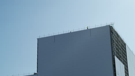 Wide-shot-of-construction-workers-working-at-height-on-a-rooftop-of-a-power-station-during-construction