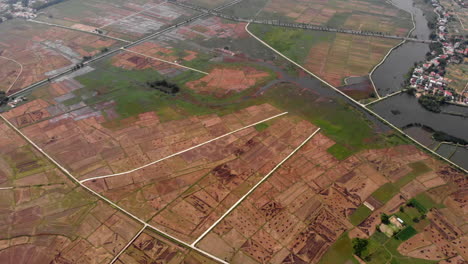 Hazy-rural-rice-paddy-fields-in-Da-Nang-Vietnam,-tilt-up-aerial
