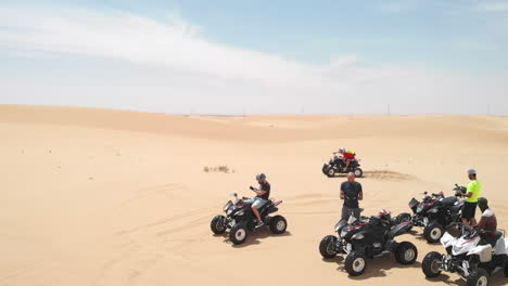 Slowmotion-aerial-drone-shot-of-friends-having-fun-in-the-desert-with-quadbikes-in-Abu-Dhabi,-UAE