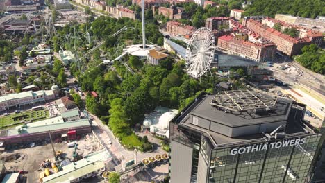 Drone-shot-at-glass-fronted-with-reflections-buildings-next-to-Liseberg-amusement,-Göteborg