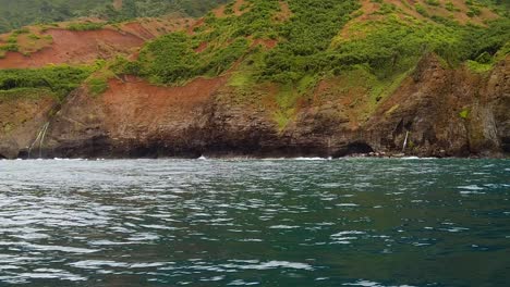 HD-120fps-Hawaii-Kauai-Bootfahren-Auf-Der-Felsigen-Küste-Des-Ozeans,-Schwenk-Von-Rechts-Nach-Links-Zum-Wasserfall-In-Der-Ferne