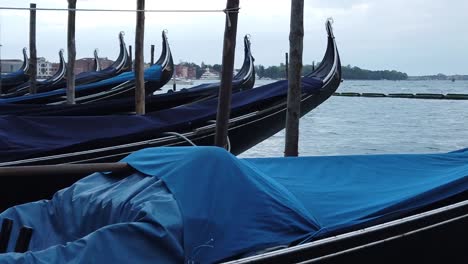 Venetian-gondolas-at-Venice-canal-dock,-rocking-in-water
