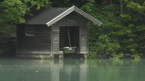 Close-up-of-a-small-boat-house-on-a-lake-in-the-forest,-a-peaceful-view