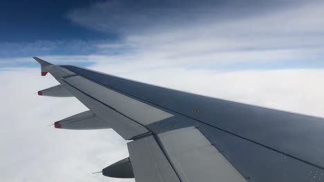 Aircraft-Plane-wing-cruising-at-high-altitude,-dense-white-clouds,-moving-fast-during-flight