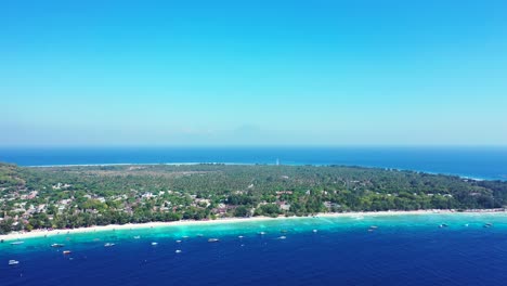Blue-Calm-Sea-With-Green-Trees-and-Clear-Blue-Sky-In-the-Background---Aerial-Shot