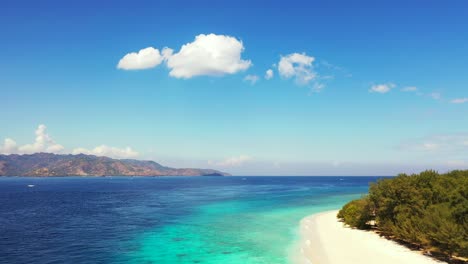 Paradise-exotic-beach-with-white-sand-washed-by-tranquil-blue-turquoise-sea-under-a-bright-blue-sky-with-overhanging-white-clouds-in-Bali