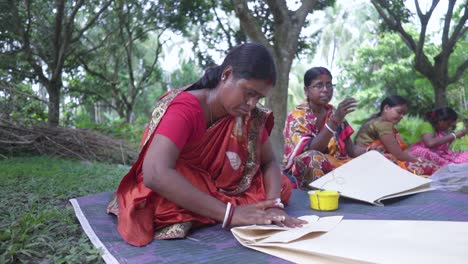 Poor-Indian-women-folding-and-making-bags-outdoor