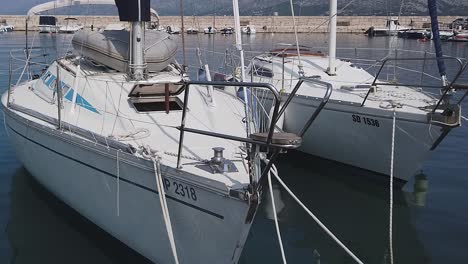 Zwei-Weiße-Segelboote-Schaukeln-Sanft,-Vertäut-In-Einem-Sonnigen-Mittelmeerhafen