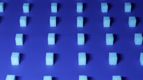 A-very-slow-tilt-down-view-of-a-unique-cubic-background-with-white-sugar-cubes-arranged-in-rows-on-a-dark-blue-background,-3D-effect