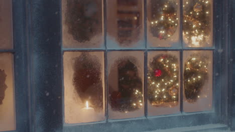 A-lit-christmas-tree-is-visible-through-the-snow-frosted-window-panes