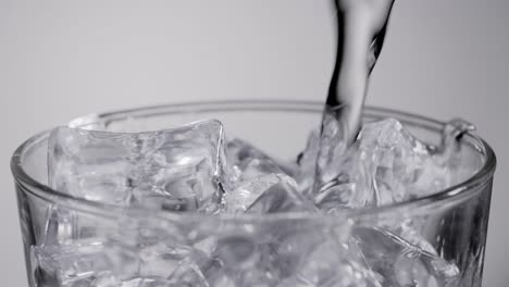 Close-up-slow-motion-water-pouring-into-glass-with-ice-cubes