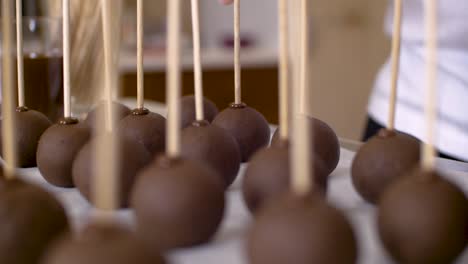 Woman-putting-wooden-stick-in-little-chocholate-ball-to-make-cakepops