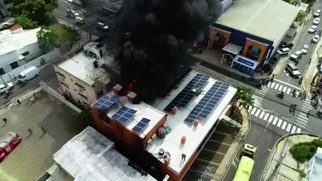 Aerial-view-of-building-on-fire,-with-solar-cells-on-roof,-in-Manila,-Philippines,-Asia,---static,-drone-shot