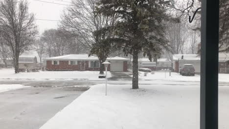 A-snowy-winter-establishing-shot-looking-out-a-window-at-a-typical-Michigan-residential-neighborhood