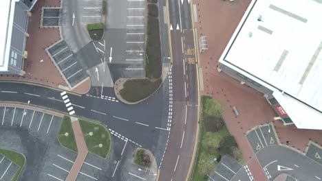 Aerial-view-above-urban-shopping-centre-empty-parking-spaces-closed-COVID-virus-town-lock-down-slow-birds-eye-reverse
