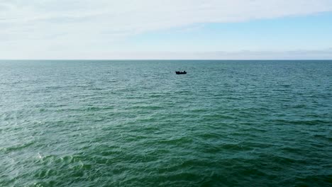 Beautiful-aerial-view-of-a-distant-fishing-boat-sailing-in-the-calm-Baltic-sea-in-sunny-day,-wide-angle-drone-shot-moving-forward