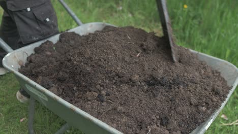 Mixing-soil-in-wheelbarrow-with-shovel-removing-roots