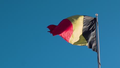 The-National-Flag-Of-Belgium-On-A-Flag-Pole-Waving-Against-The-Blue-Sky