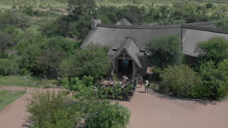 Aerial-view-of-people-leaving-safari-vehicle-and-heading-into-lodge