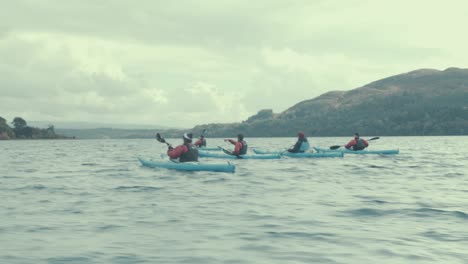 Friends-paddle-kayaks-on-lake-scenic-tracking-shot