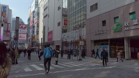 Japanese-people-walking-through-street-towards-pop-culture-stores-on-sunny-day-in-Tokyo