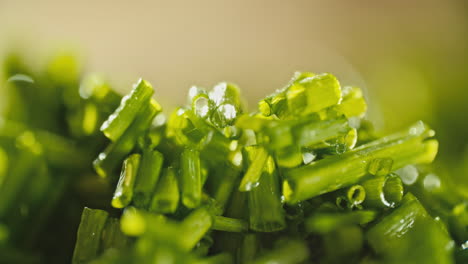 close-macro-shot-of-fresh-chopped-chives-laying-on-a-wooden-cutting-board,-then-water-is-sprayed-on-it