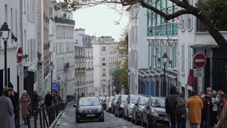 Schwenkaufnahme-Von-Menschen,-Die-In-Der-Montmartre-Straße-Spazieren-Gehen,-Während-Ein-Auto-Die-Straße-Hinauffährt