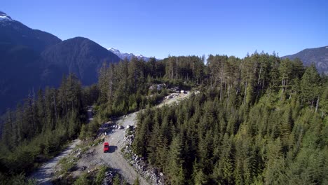 Approaching-aerial-view-of-a-red-Jeep-parked-on-the-mountain-backroad-trails-in-Mission-BC