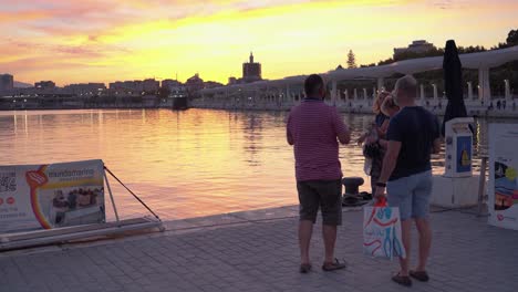 Menschen-An-Der-Promenade-Palmeral-De-Las-Sorpresas-In-Málaga,-Spanien-Bei-Einem-Sonnenuntergang-–-Goldene-Stunde-–-Weitwinkelaufnahme