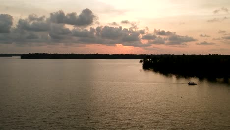 Beautiful-aerial-shot-of-a-backwater-Vembanadu-Lake,water-lines,twilight-sunset,coconut-trees-,water-transportation,clouds,reflation,House-boat,Water-lines