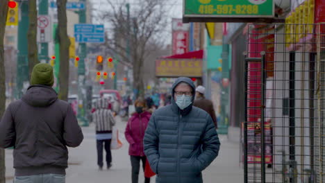 Fußgänger,-Die-Mit-Chirurgischen-Masken-Eine-Belebte-Straße-In-Toronto-Entlanglaufen