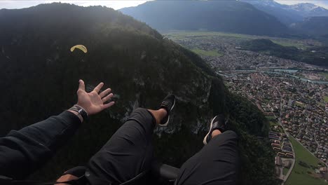 POV-shot-of-a-young-man-stretching-his-arm-and-hand-out-in-joy,-happiness-and-excitement-over-the-ride-in-the-air-over-Interlaken-village-in-Switzerland