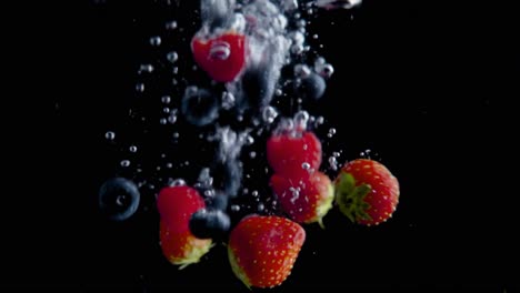 Fresas-Cayendo-Al-Agua-En-Cámara-Superlenta,-Fondo-Negro,-Muchas-Burbujas-De-Aire,-4k240fps