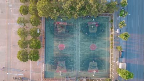 Top-down-Shot-Of-A-Basketball-Court-With-Players-Playing-On-A-Sunny-Morning-In-Thessaloniki,-Greece---aerial