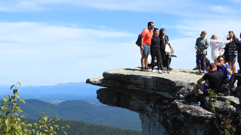 Groups-of-people-taking-group-pictures-while-standing-on-the-McAfee-Knob-with-a-view-of-the-mountains-in-the-background