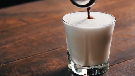Hot-coffee-is-poured-into-a-glass-full-of-hot-milk-and-foam-in-slow-motion