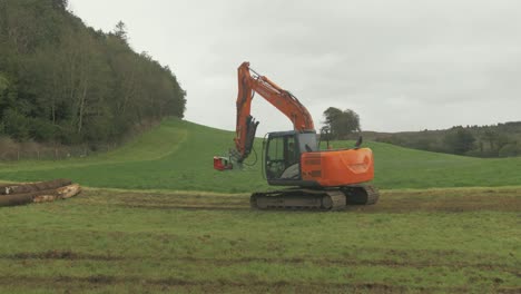 Digger-excavator-with-tree-shear-attachment-driving-in-field-towards-forestry